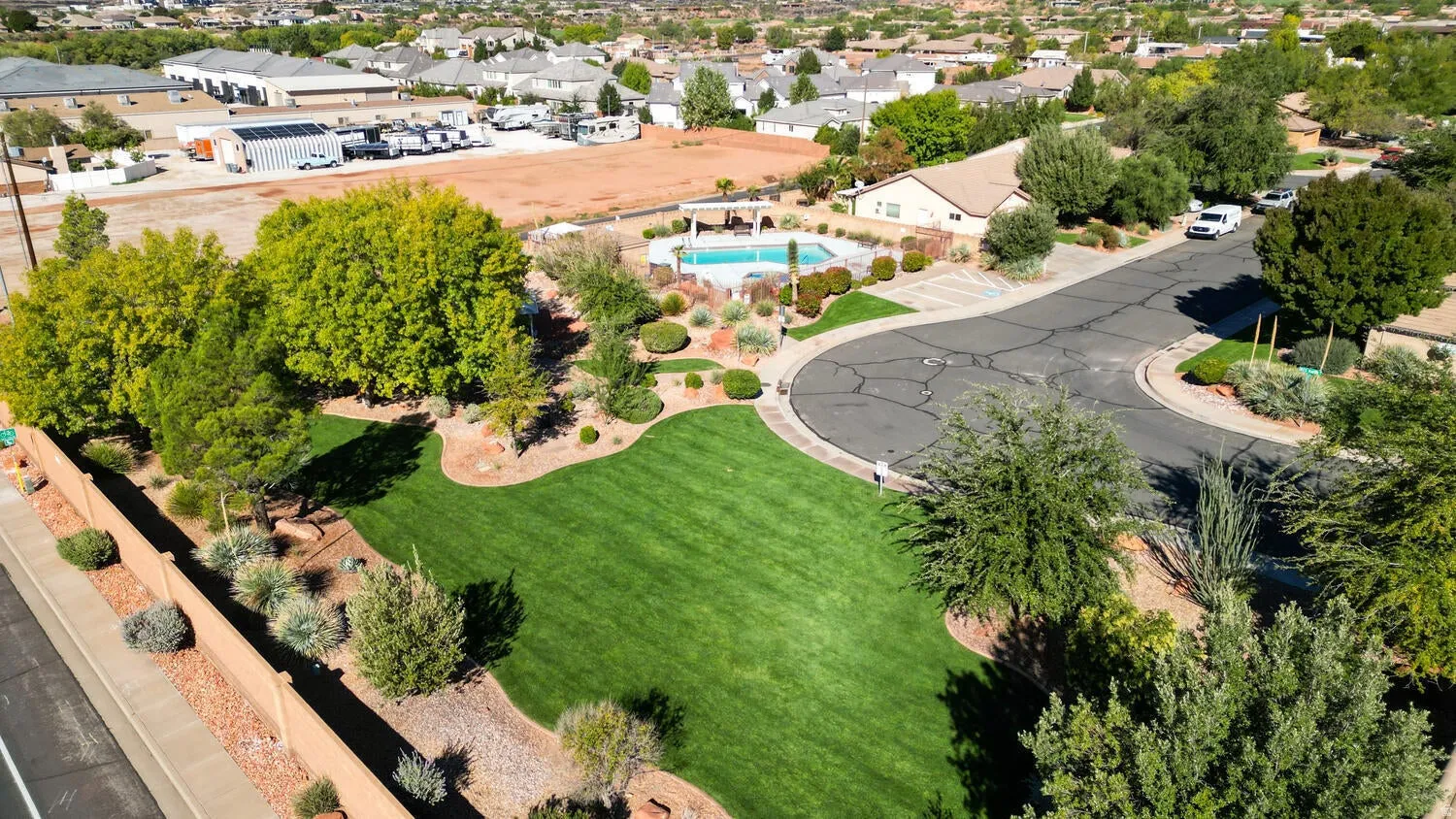 Manicured lawn with mature trees, established landscaping, cul-de-sac street, and a community pool