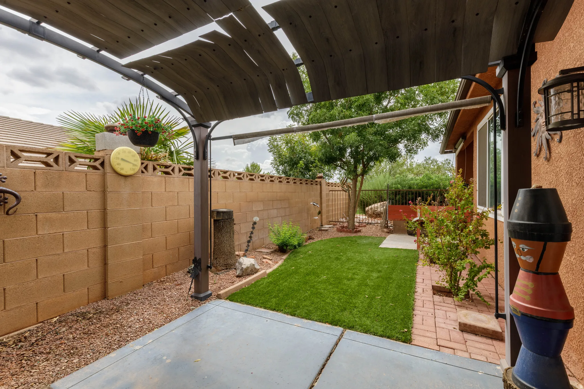 Covered patio structure, concrete patio, artificial turf, perimeter block wall, and brick-edged landscaping