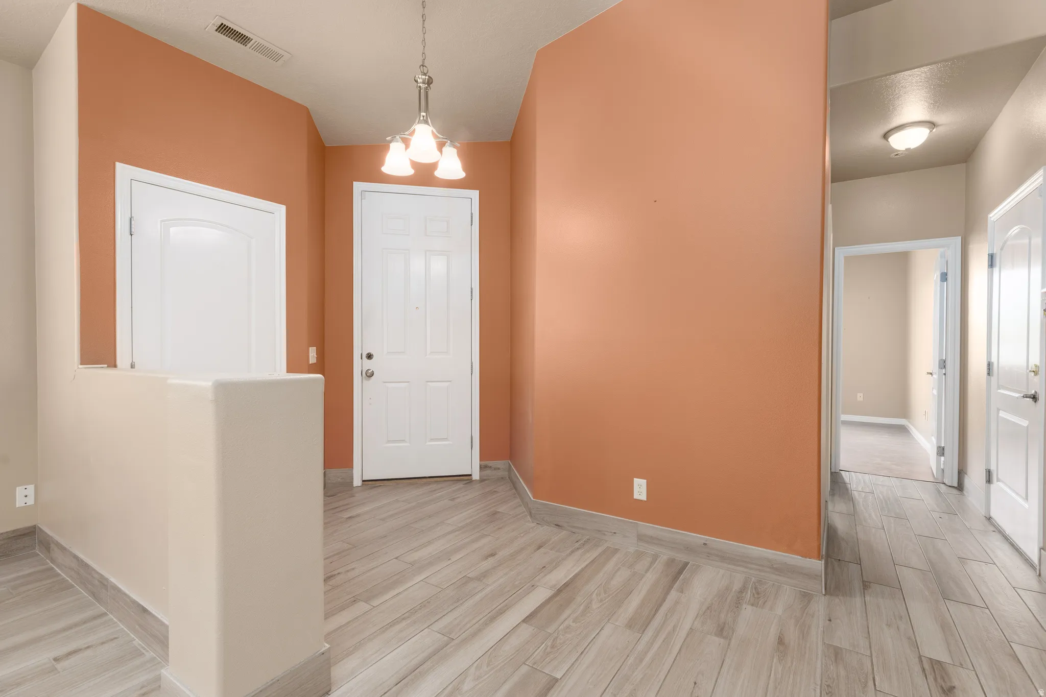 Wood-finish flooring, overhead lighting, paneled interior doors, textured walls, and a half wall partition