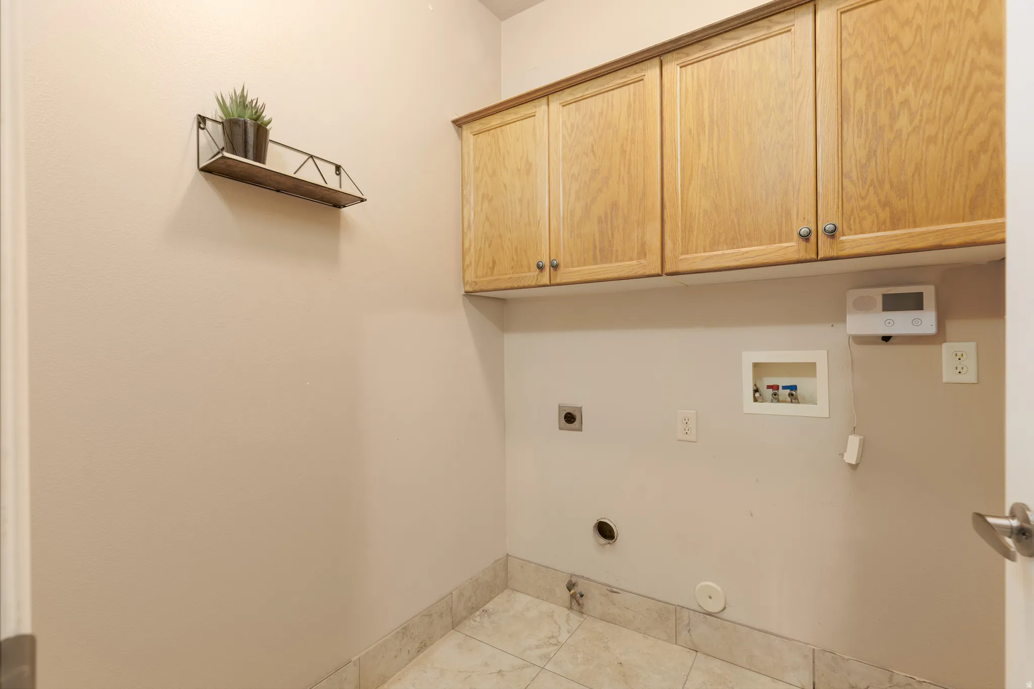 Wood-finish cabinetry with silver-tone hardware, tile flooring, and utility hookups
