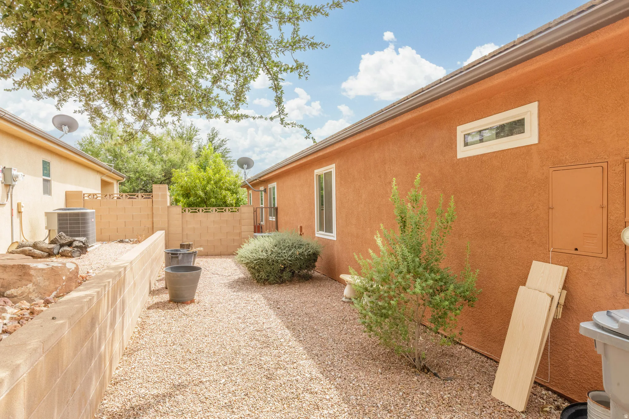 Stucco exterior with a rectangular window, a horizontal transom window, and a rain gutter system