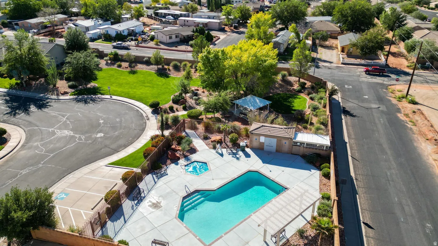 Outdoor pool, integrated spa, adjacent covered patio, surrounding landscaped areas, and nearby green spaces