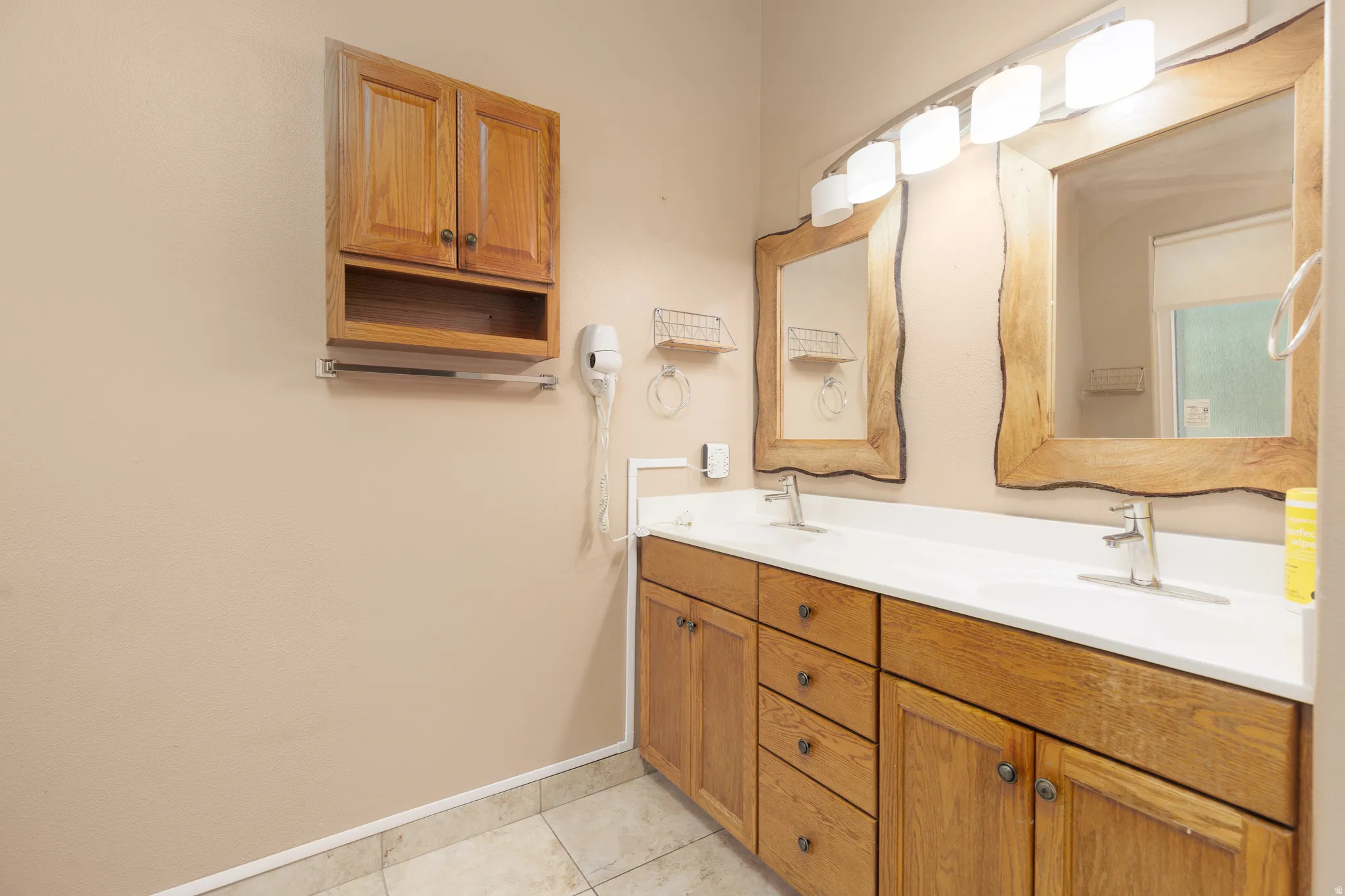 Dual vanity with integrated white sinks, wood-finish cabinetry, and framed mirrors