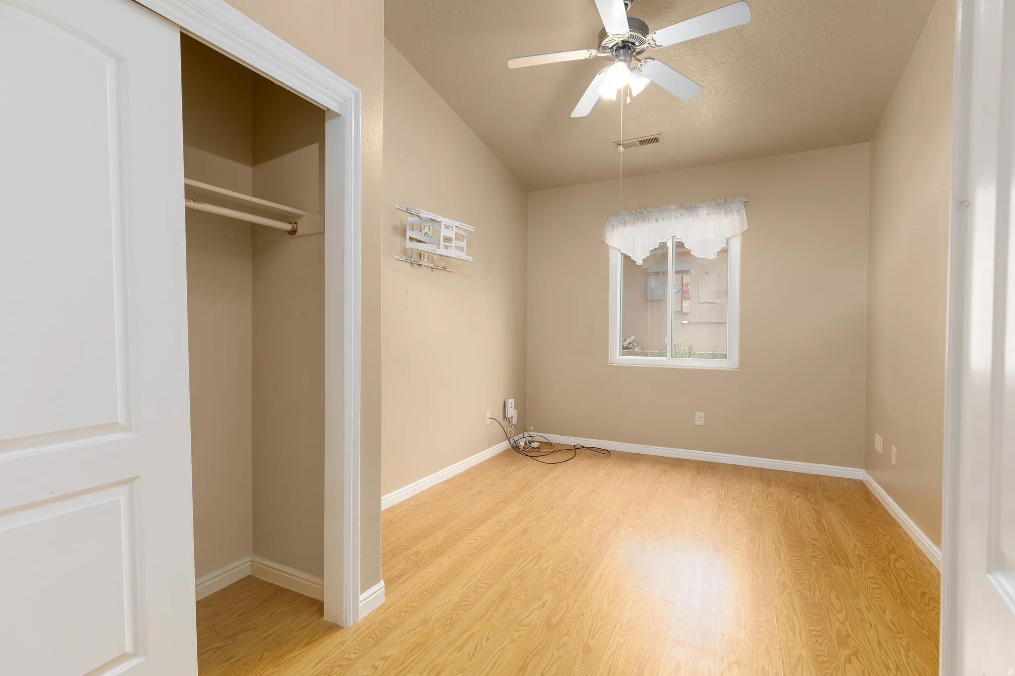 Sliding closet doors, wood-finish flooring, vaulted ceiling, ceiling fan, and a single window