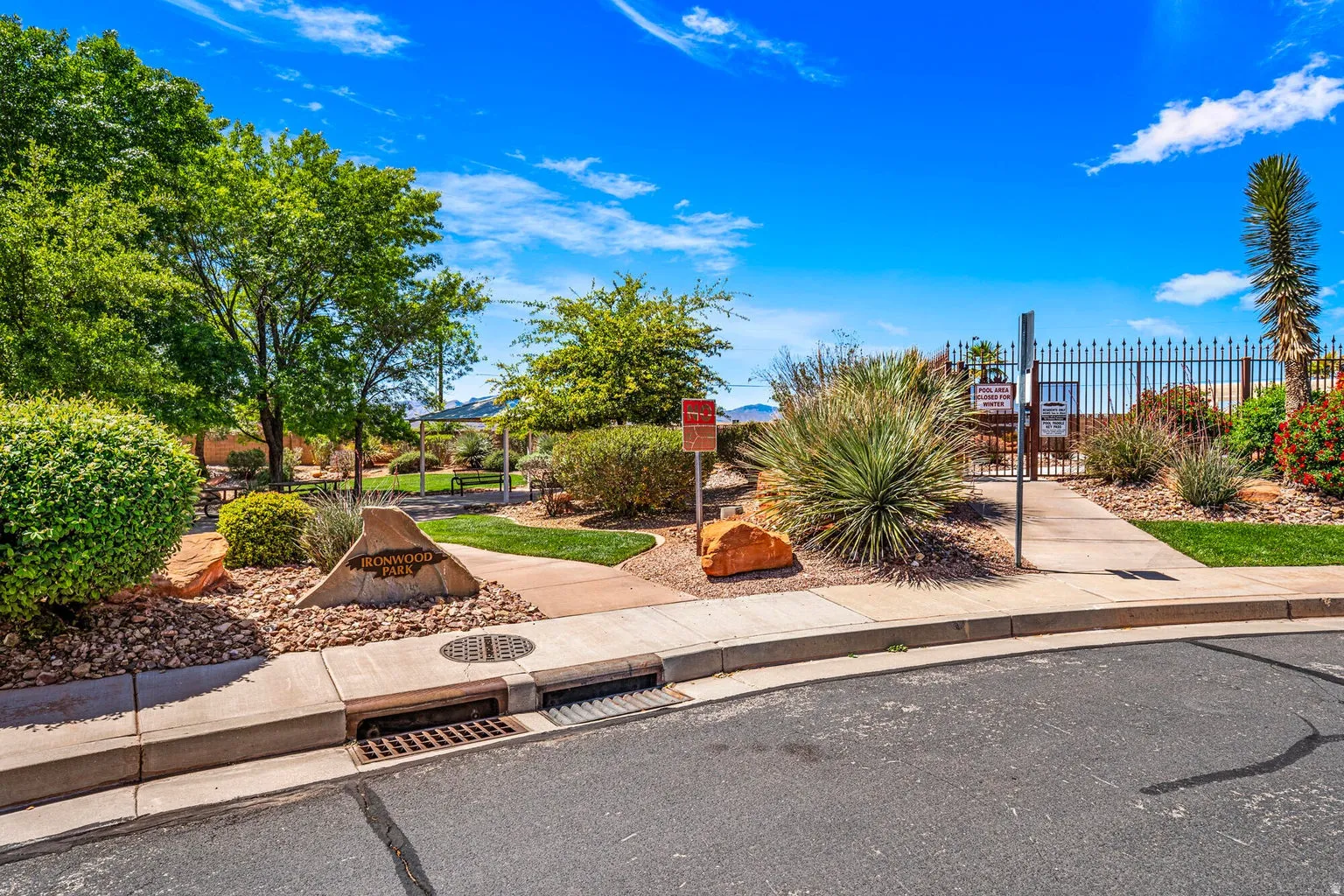 Landscaped park area featuring mature trees, concrete pathways, and decorative rock elements