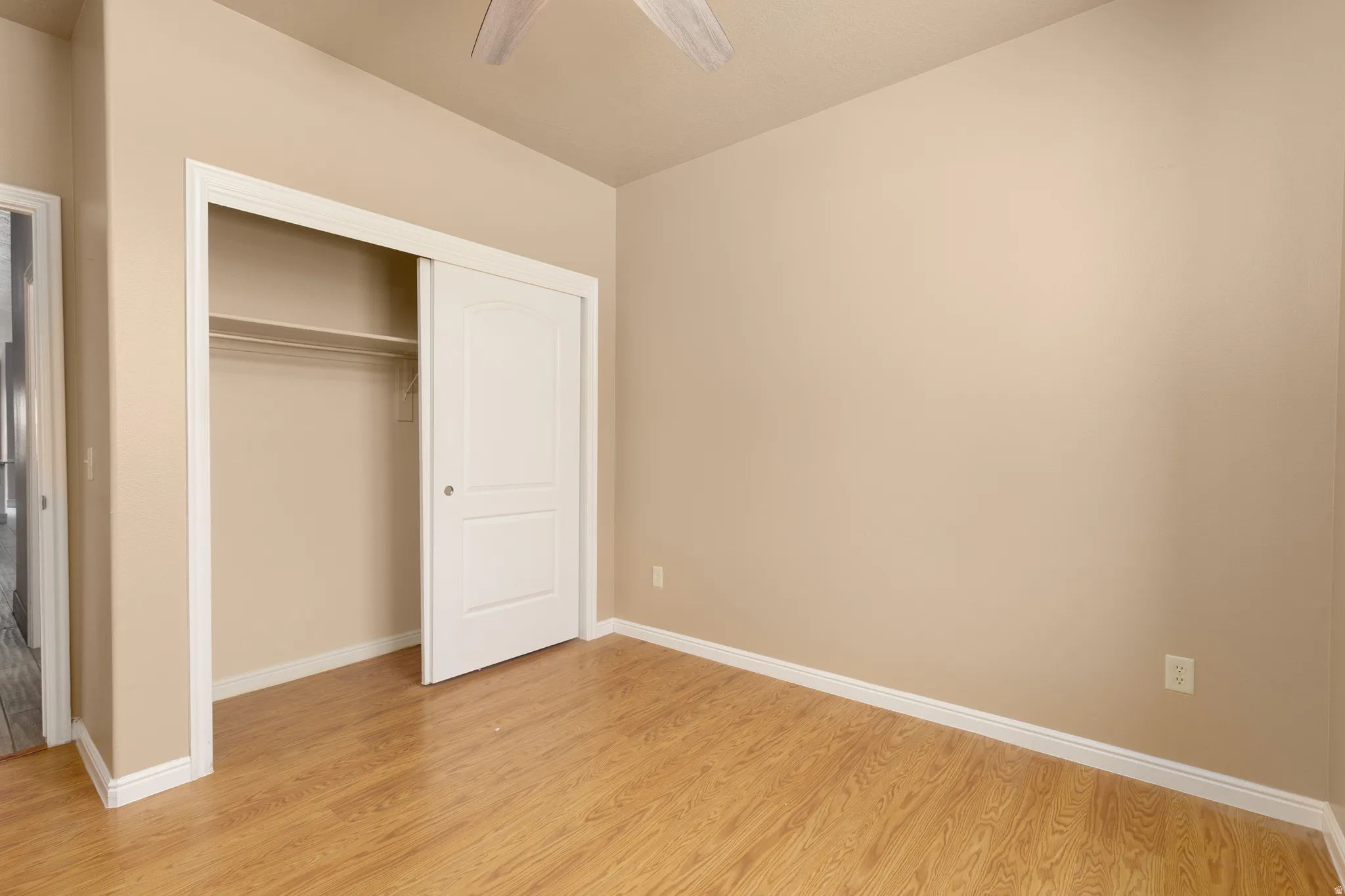 Wood-finish flooring, neutral-toned walls, and a ceiling fan