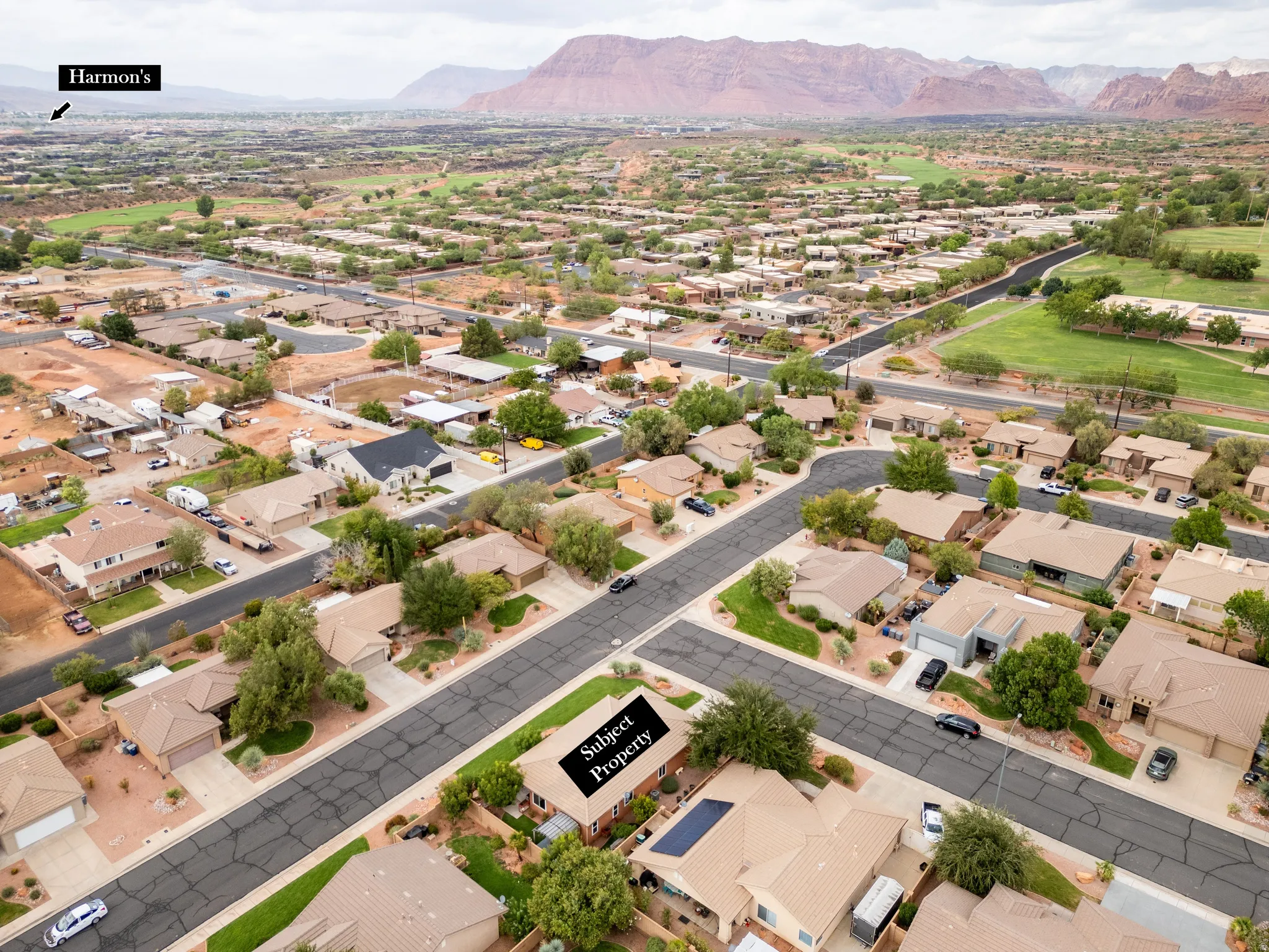 Property with a solar panel array, attached garage, and mature landscaping