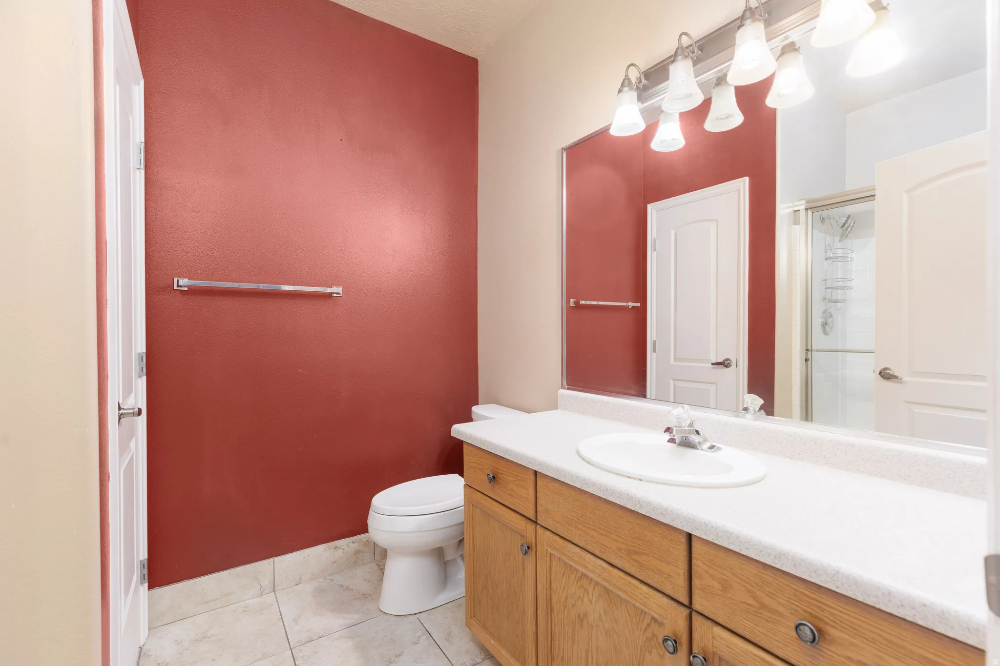 Bathroom featuring a light wood-finish vanity with an integrated sink, a large mirror, and tiled flooring