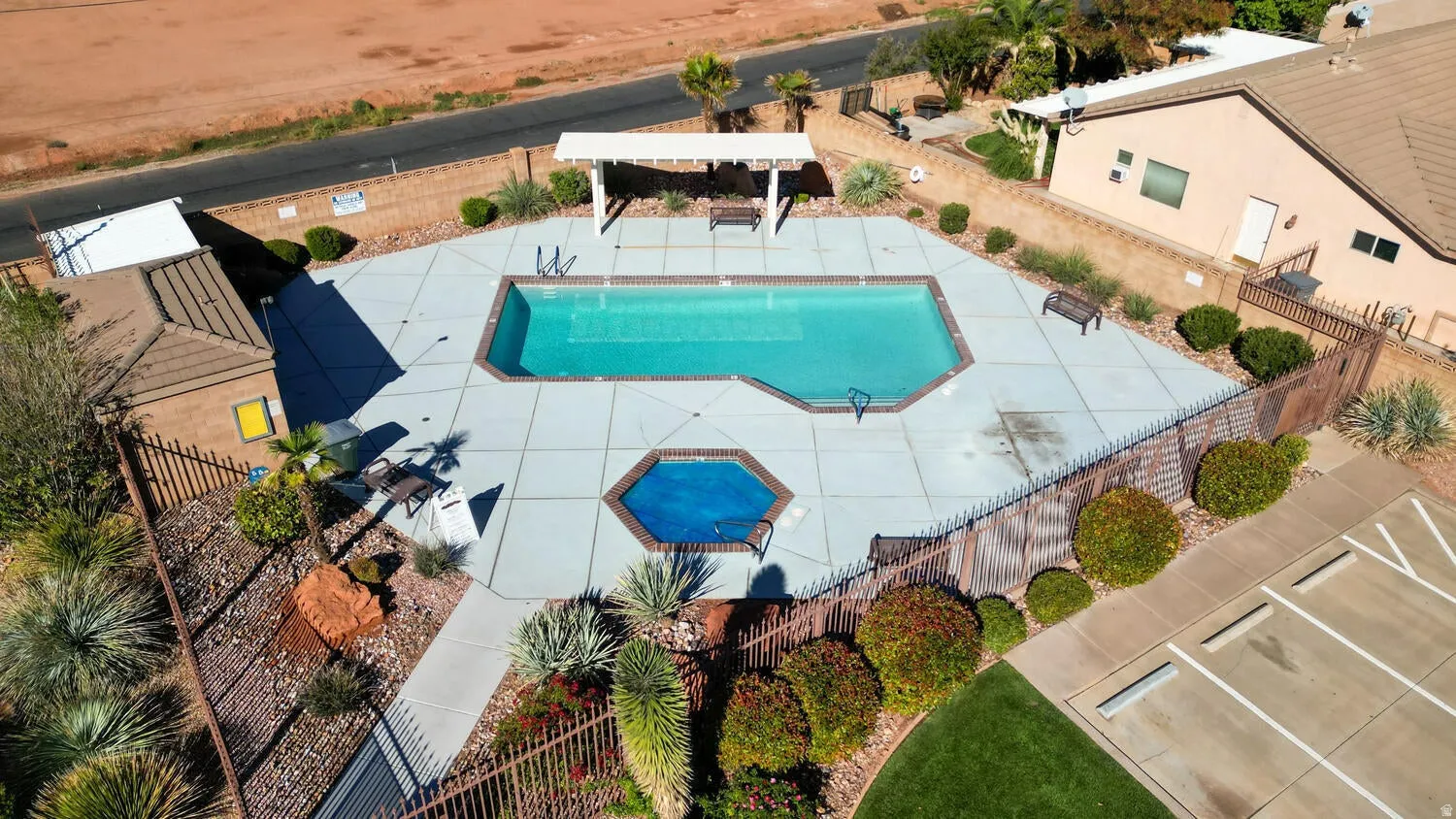 Swimming pool with integrated spa, surrounding concrete patio, and a shaded pergola