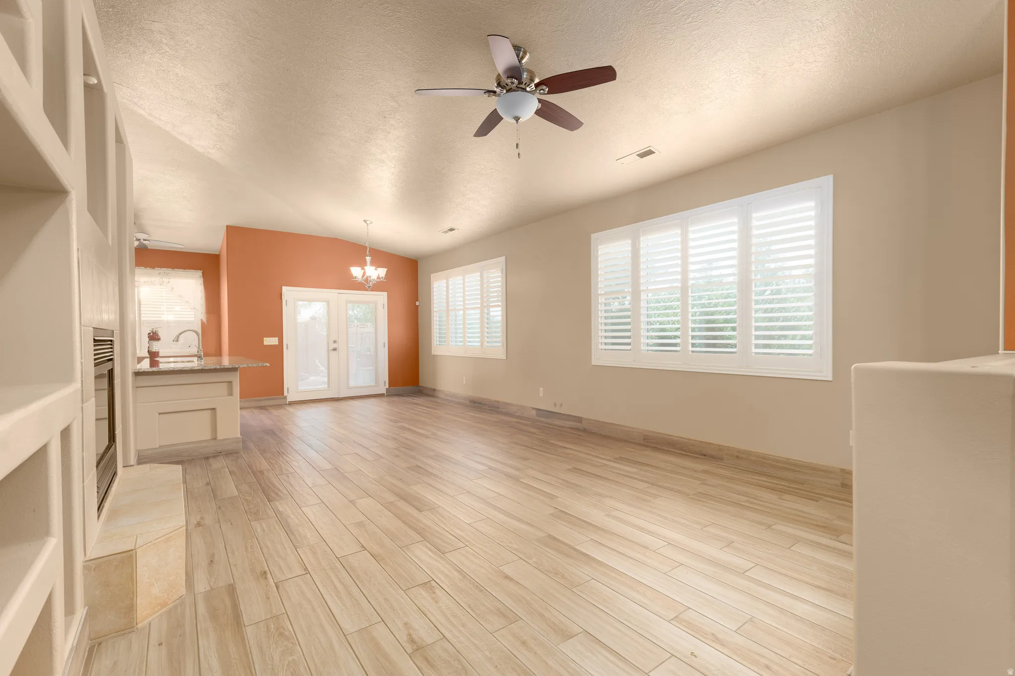 Vaulted ceilings, wood-finish flooring, built-in shelving, ceiling fan, and window shutters
