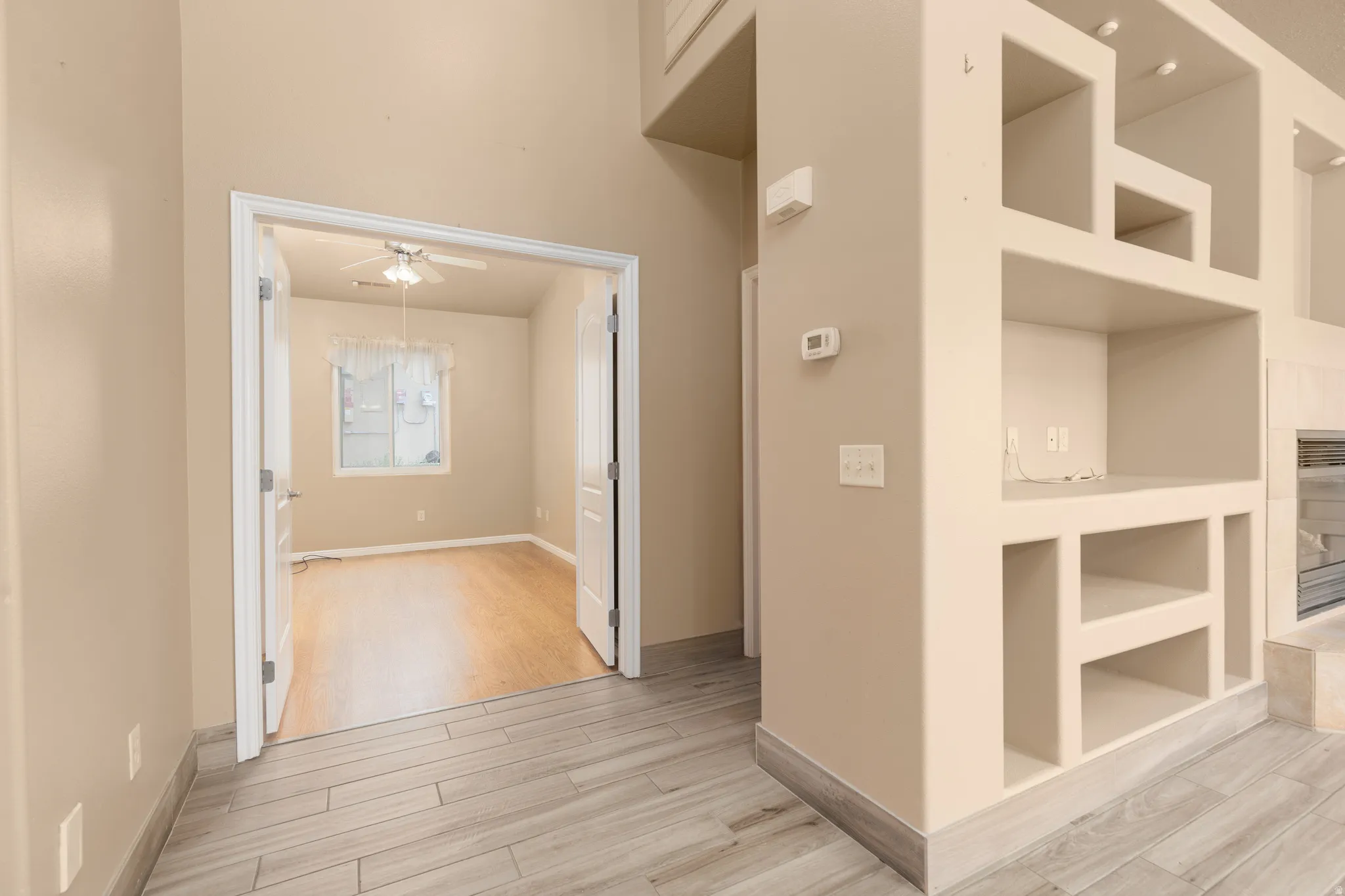 Built-in shelving unit, recessed ceiling lighting, wood-finish flooring, and French doors