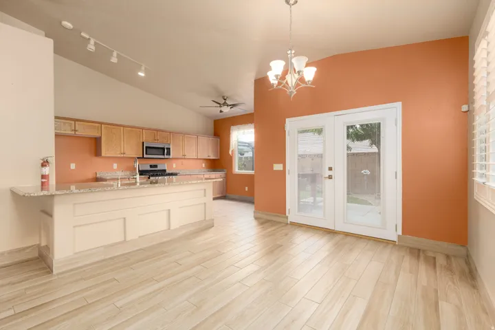 Vaulted ceilings, wood-look flooring, central island with an integrated sink, built-in microwave, and double glass-paneled doors