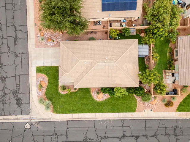 Pitched roof, front lawn with curved landscaping, desert-style landscaping with rocks and shrubs, paved driveway, mature trees