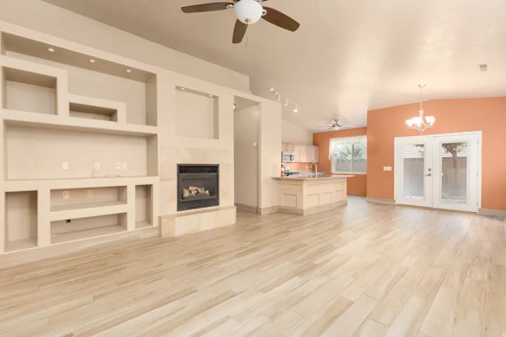 Recessed display shelving, built-in fireplace, vaulted ceiling, wood-finish flooring, and French doors