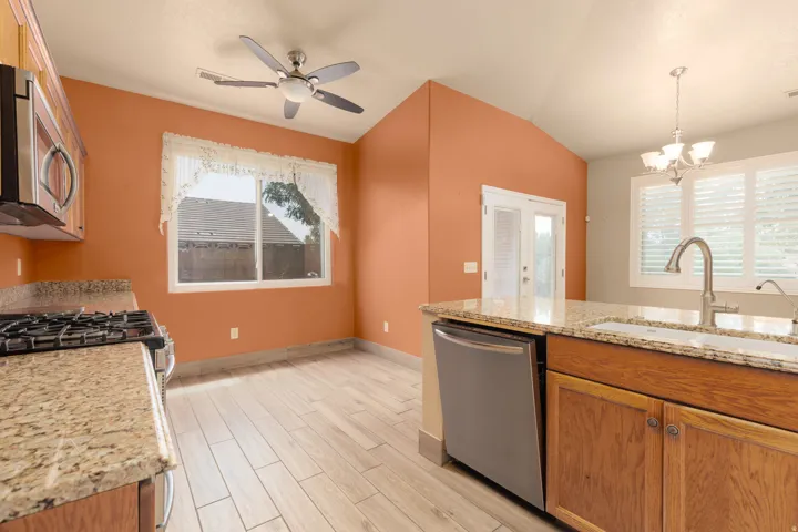 Kitchen featuring wood-finish flooring, granite countertops, stainless steel appliances, and a vaulted ceiling