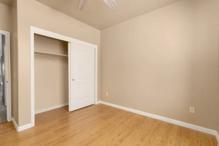 Wood-finish flooring, neutral-toned walls, and a ceiling fan