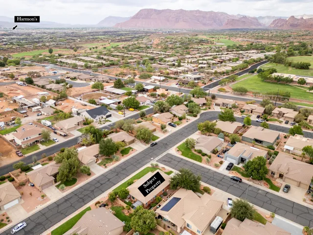 Property with a solar panel array, attached garage, and mature landscaping