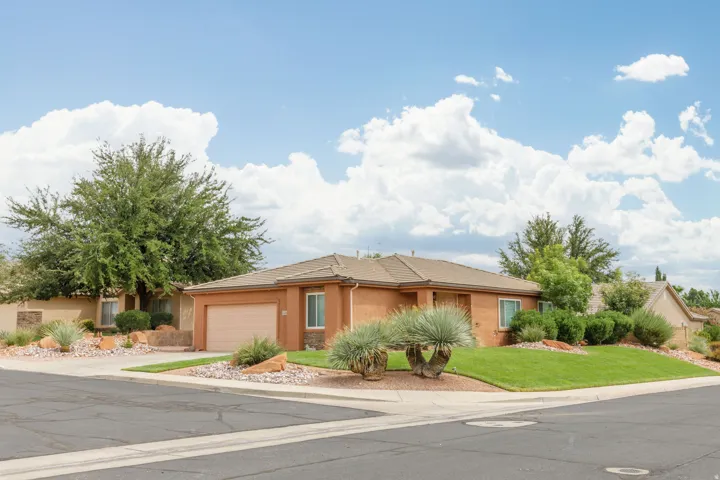 Corner lot property featuring a stucco exterior, an attached garage, and a concrete driveway