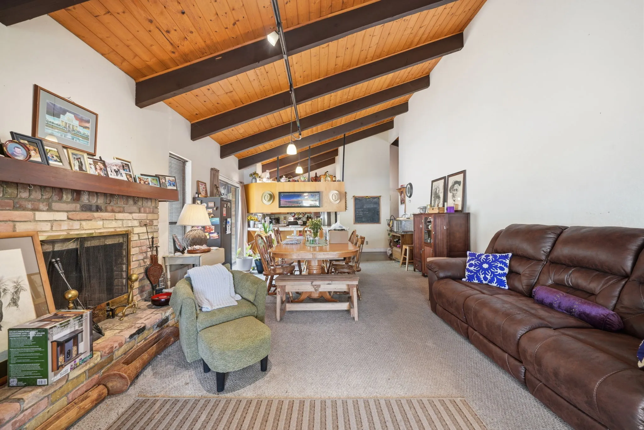 Vaulted wood-paneled ceiling with exposed beams, brick fireplace, track lighting, and built-in cabinetry