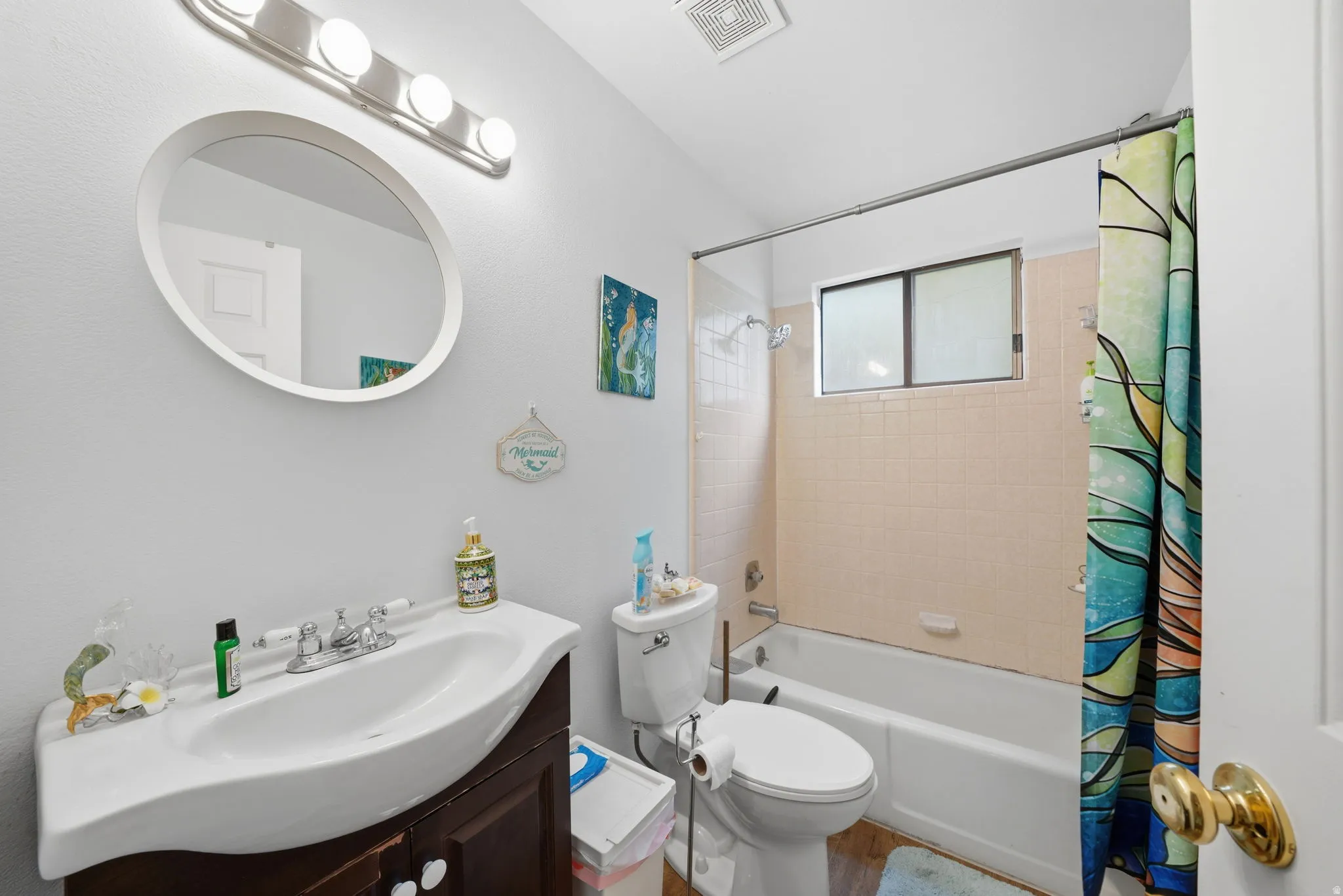 Bathroom featuring a white bathtub, tiled shower surround, and a window for natural light