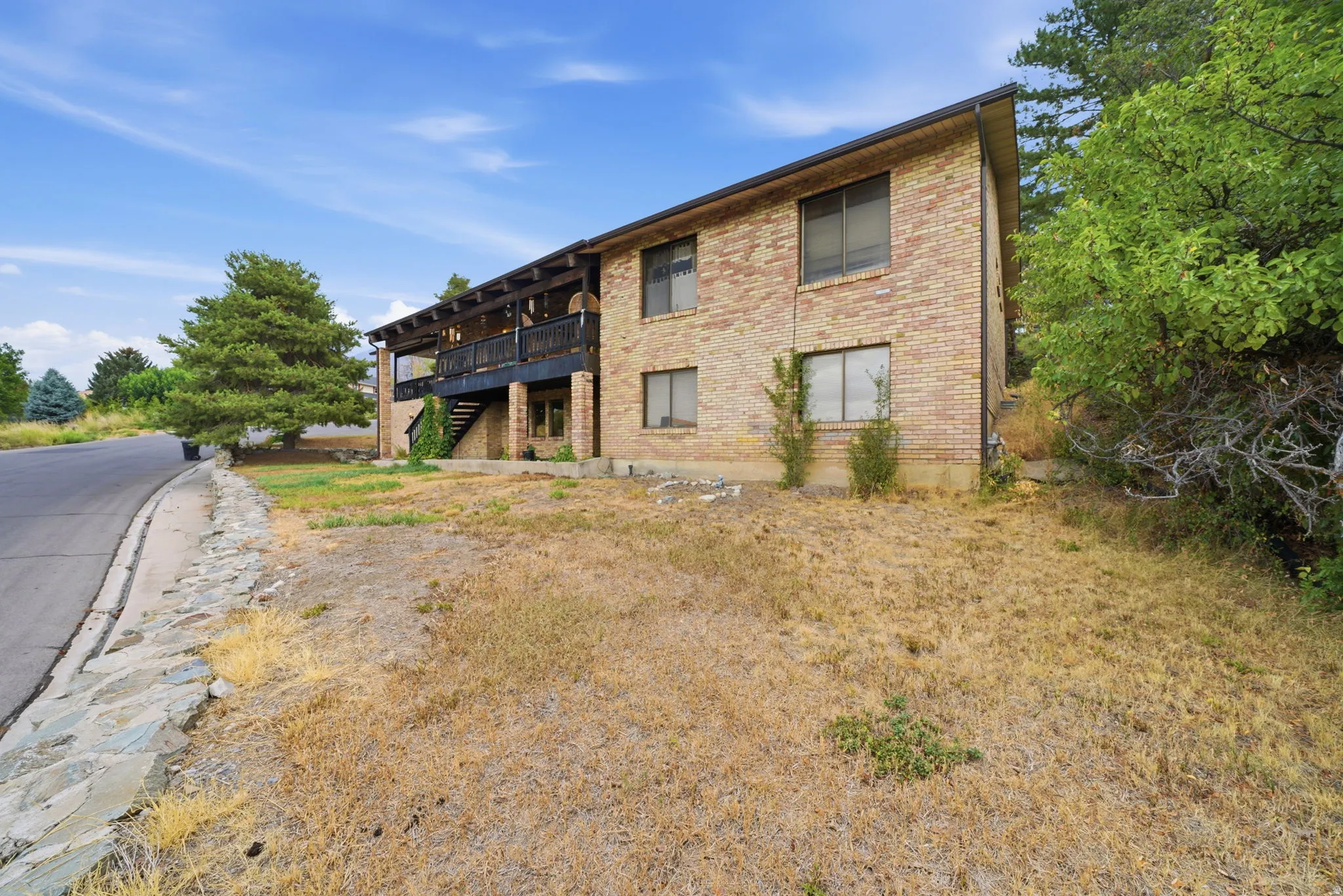 Brick exterior with a second-story covered deck and a lower-level covered patio