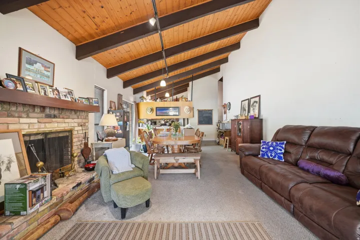 Vaulted wood-paneled ceiling with exposed beams, brick fireplace, track lighting, and built-in cabinetry