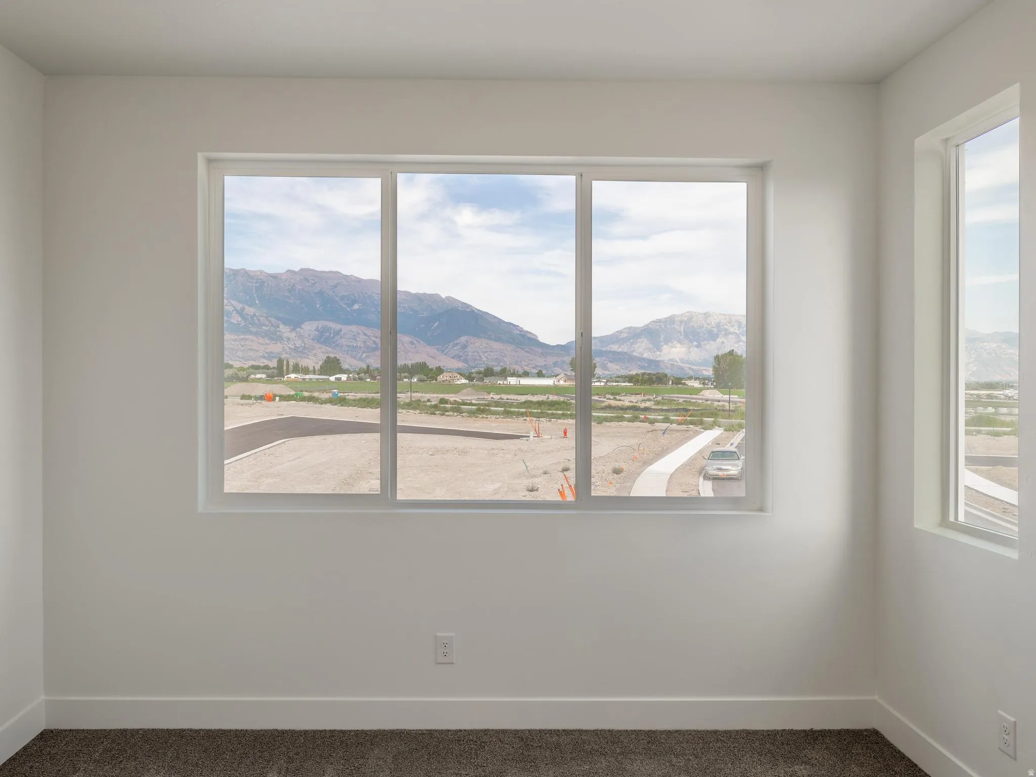 Neutral wall color, multiple windows, mountain backdrop, and carpeted flooring