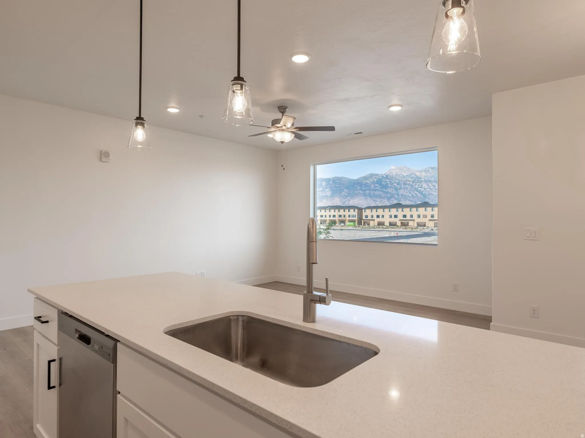 Kitchen island with a stainless steel sink, stainless steel dishwasher, and light-colored countertop