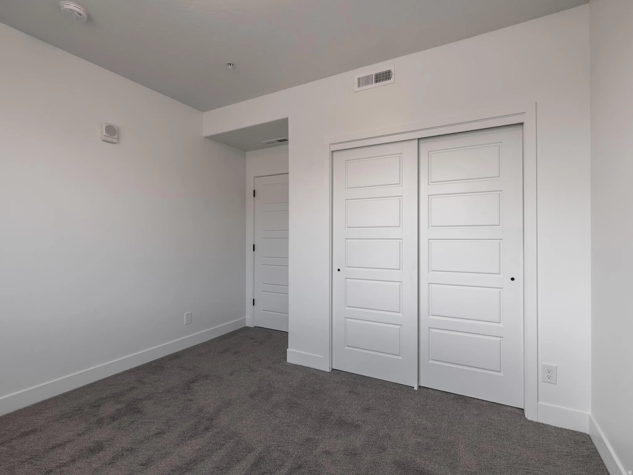 Sliding panel doors, wall-to-wall carpeting, and bright white walls
