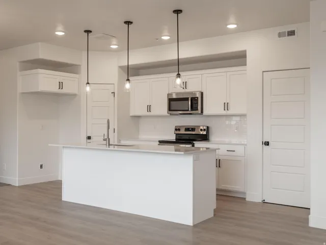 Modern kitchen featuring white shaker cabinetry, stainless steel appliances, a center island with sink, subway tile backsplash, and recessed lighting