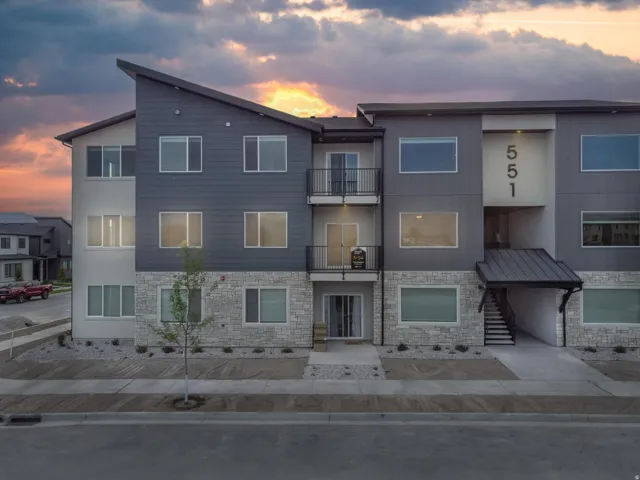 Modern architectural design with a sloped roofline, stone veneer detailing, and dark siding
