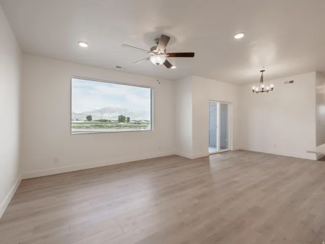 Spacious room featuring wood-finish flooring, a large picture window, recessed lighting, and a ceiling fan