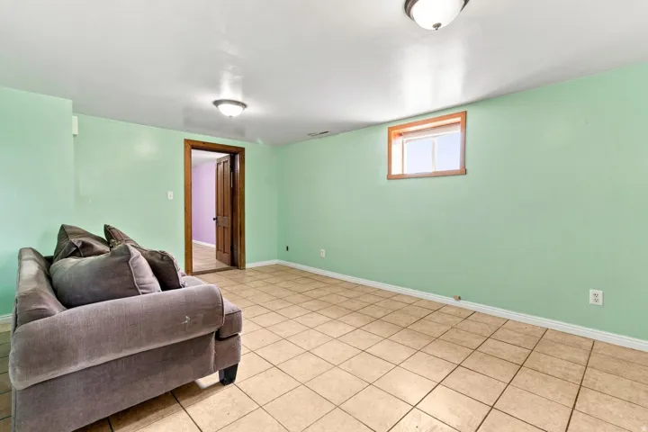 Tile flooring, light green wall finishes, wood-trimmed window, and wood-trimmed doorway