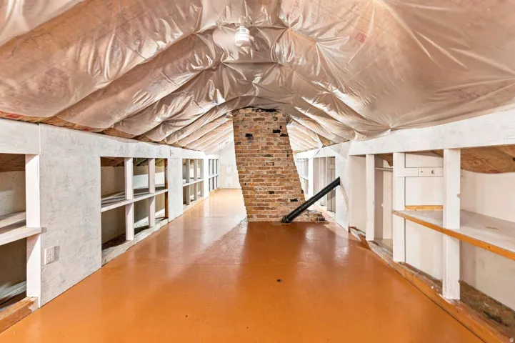 Spacious loft-style interior with soaring vaulted ceilings, exposed brick chimney, and polished concrete flooring