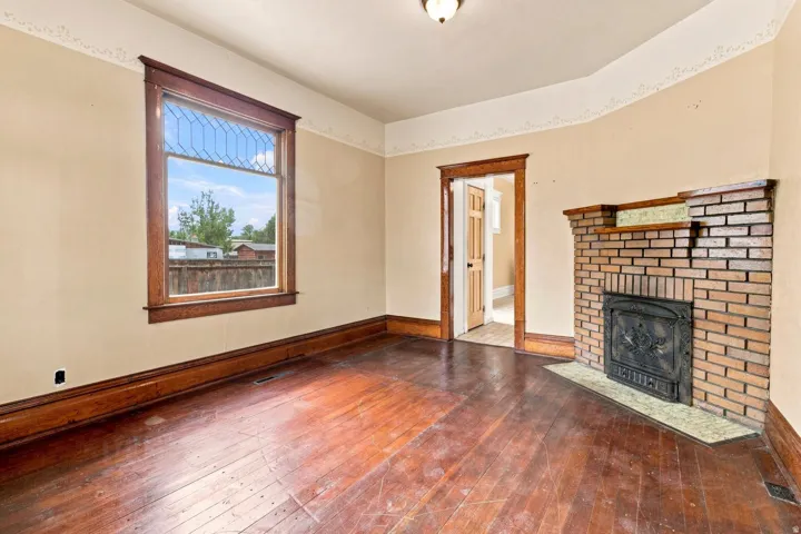 Hardwood flooring, brick fireplace with decorative insert, and a transom window with geometric detailing