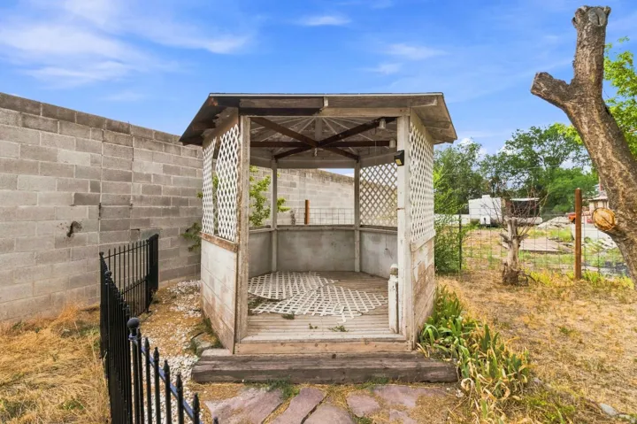 Detached outdoor structure featuring lattice-panel walls, open-air design with partial screening, wood-beam roof framing, and concrete slab flooring