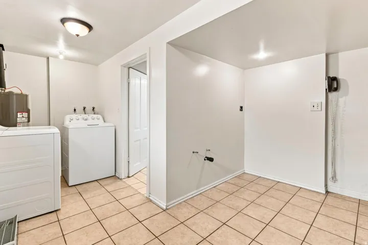 Laundry area with neutral tile flooring, overhead lighting, and white walls