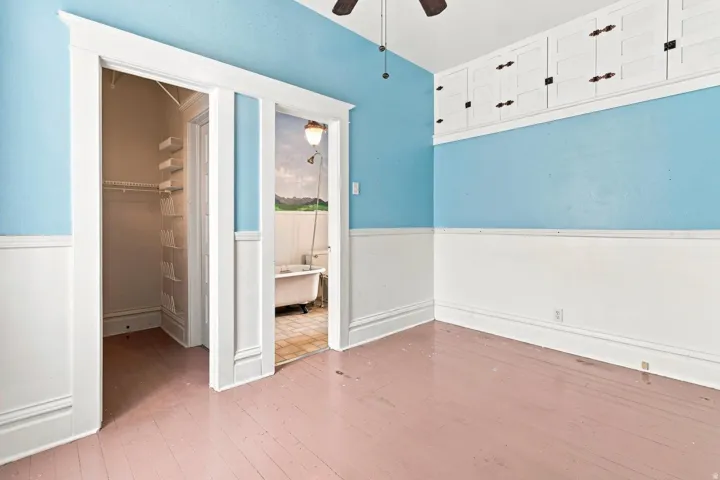 Built-in cabinetry, painted wood flooring, and a ceiling fan