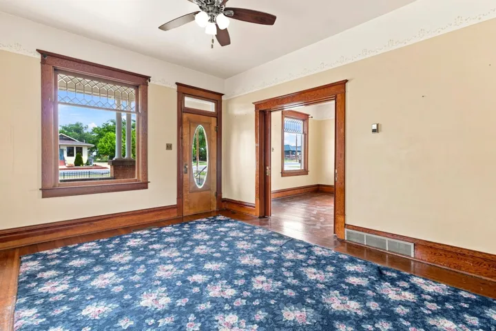 Wood-finish flooring, decorative trim, and a ceiling fan with integrated lighting