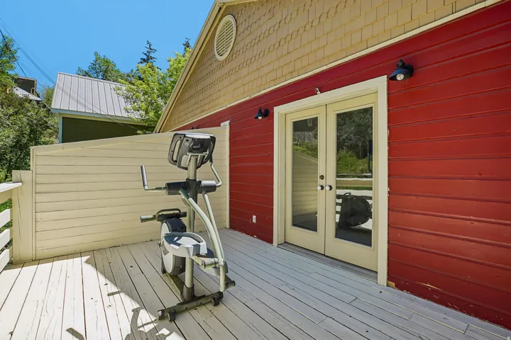 Outdoor deck with painted wood flooring, privacy wall, and double glass-paneled doors