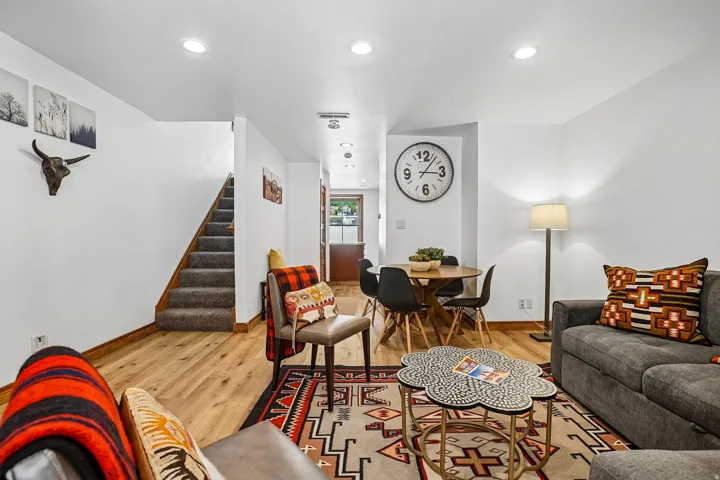 Wood-finish flooring throughout, recessed lighting, and a carpeted staircase with wood railing