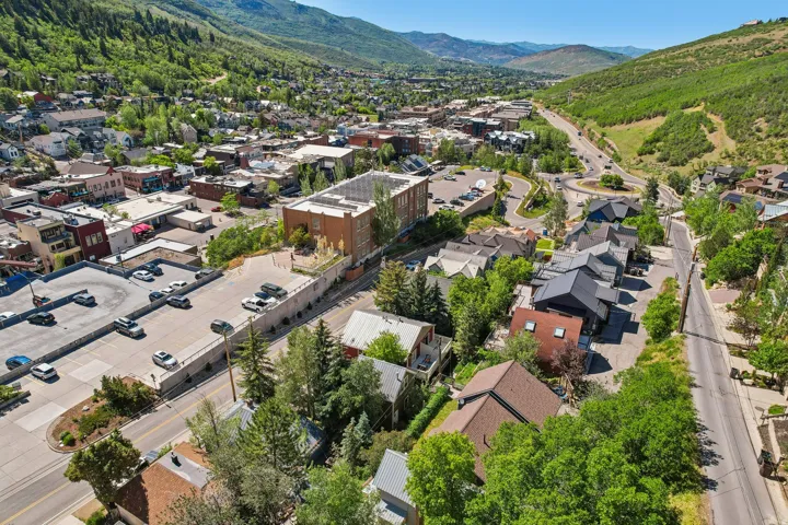 Mountainous terrain backdrop featuring a development of residences with varied rooflines and surrounding mature trees, offering multiple streets and a rotary