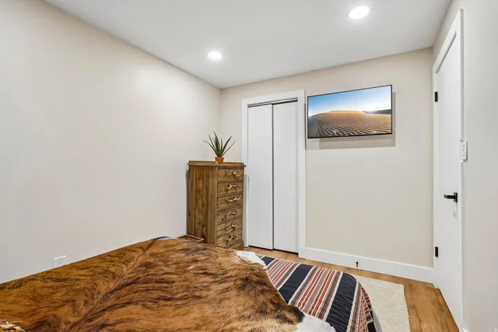 Bedroom featuring warm wood-finish flooring, recessed ceiling lighting, and a wooden dresser with multiple drawers
