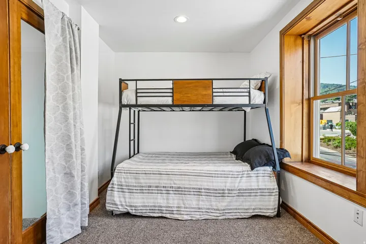 White walls, recessed ceiling light, wood-framed window, natural wood trim, and grey carpeting