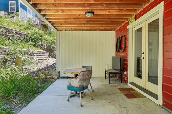 Covered concrete patio with exposed wood joists and a privacy wall