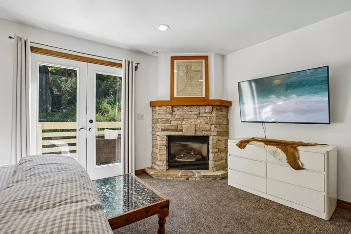 Corner stone fireplace with wood mantel, double French doors, and recessed lighting