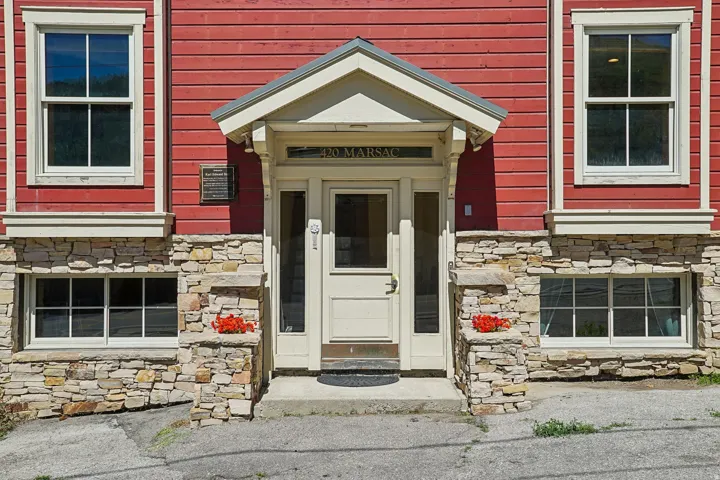 Exterior featuring red horizontal siding, a stone facade, and white trim