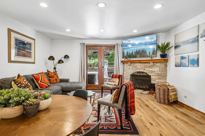 Recessed lighting illuminates the wood-finish flooring and a stone-clad fireplace