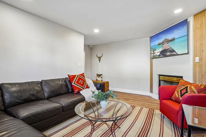 Recessed ceiling lighting, wood-finish flooring, built-in fireplace, and a decorative slatted wood wall accent