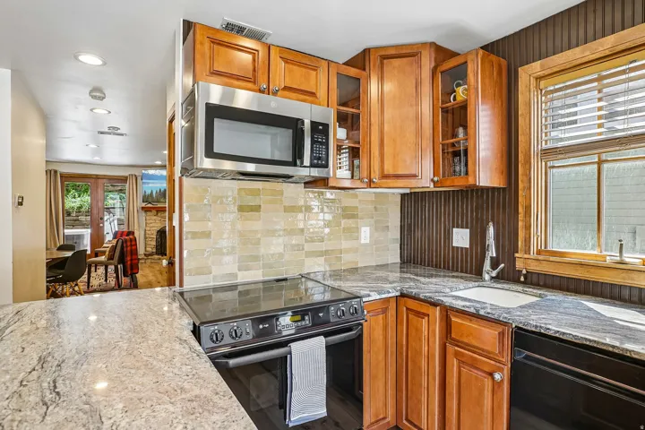 Kitchen featuring granite countertops, wood cabinetry, stainless steel microwave, and an electric range with a built-in oven